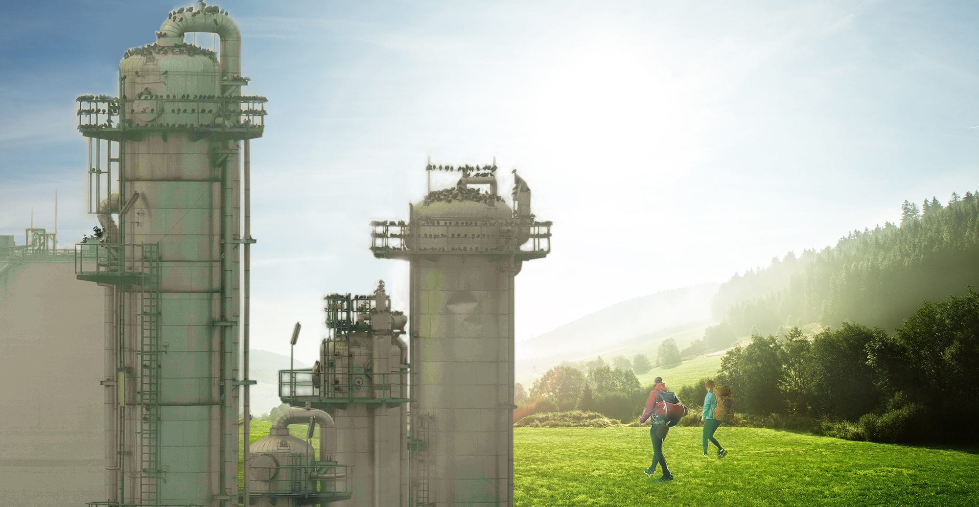 Produktionsanlage, dahinter eine grüne Landschaft, über welche zwei Personen wandern.