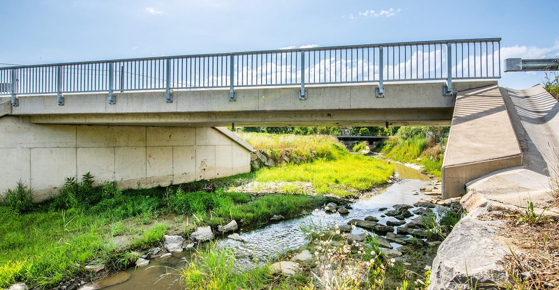 Foto einer Brücke über einem kleinen Bach mit Hochwasserschutzmaßnahmen.