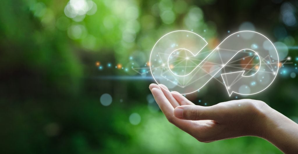 A hand holds the symbol of the circular economy. Symbolic image for climate neutrality