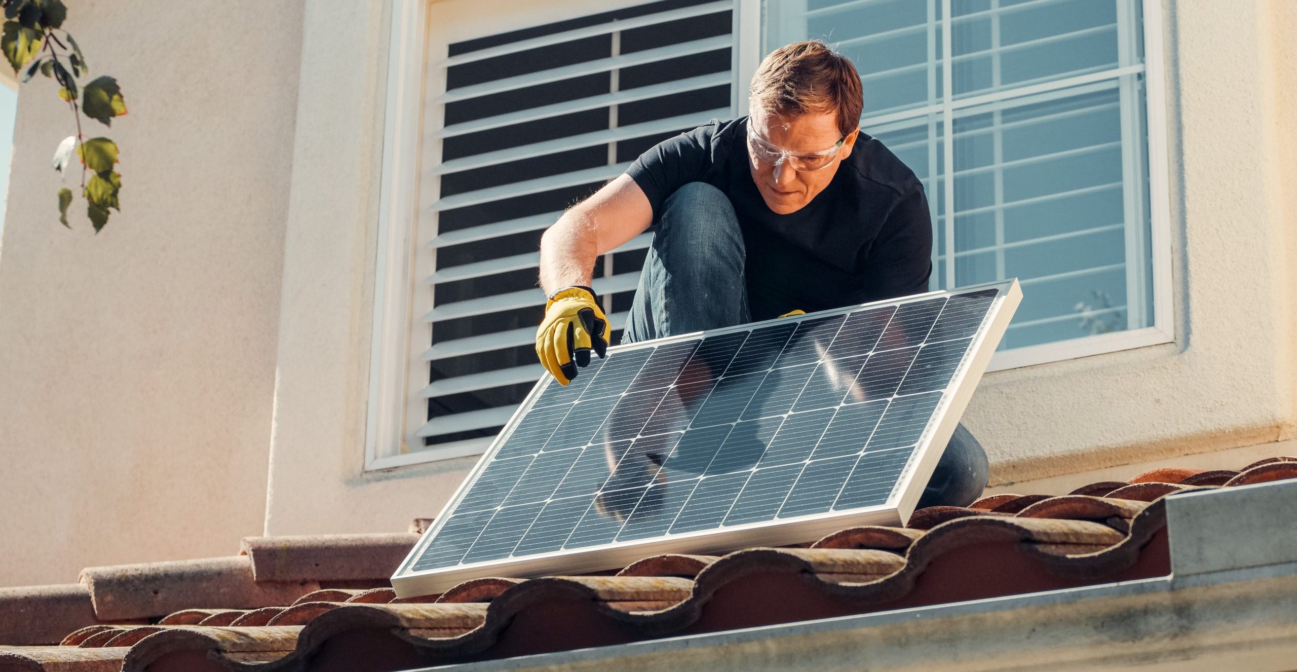 Ein Mann montiert ein Solarpanel auf ein Dach.