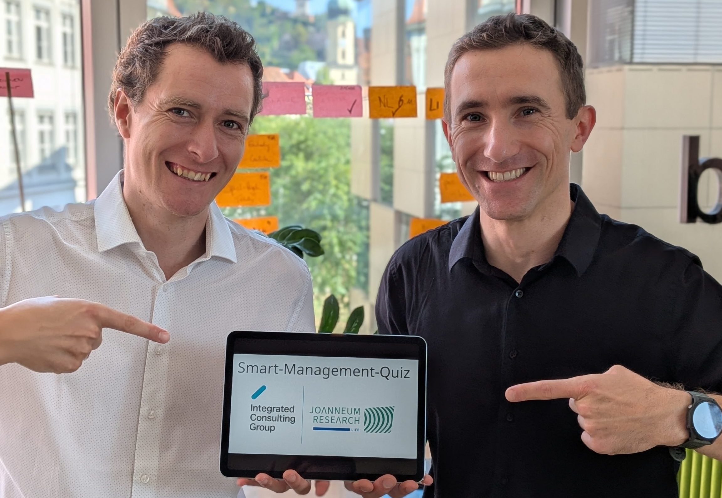 Foto von Roberl Merl von der Integrated Consulting Group und Stephan Schwarzinger von JOANNEUM RESEARCH mit einem Tablett, auf dem das Quiz zu sehen ist.