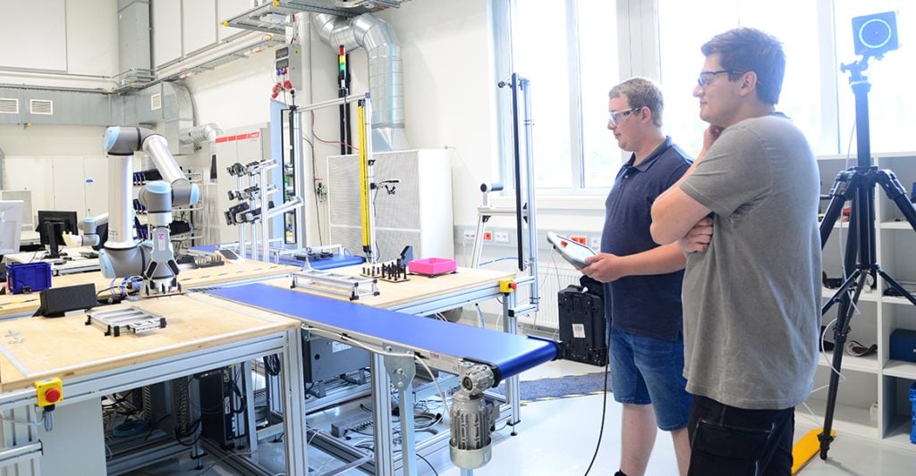 Two apprentices in front of the hands-on area, our robotics testing platform