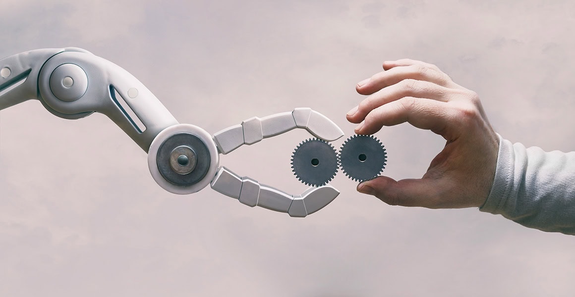 Roboterhand und Menschenhand halten jeweils ein Zahnrad, welche in sich verzahnt sind