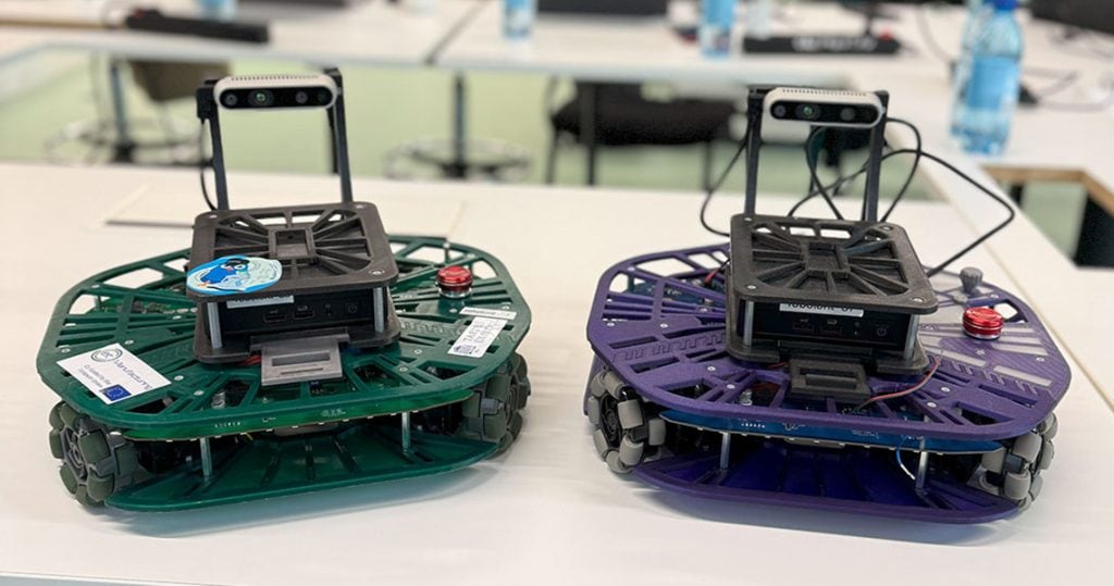 Zwei kleine mobile Roboter stehen auf einem Tisch