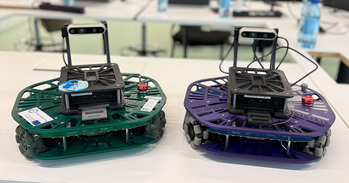 Zwei kleine mobile Roboter stehen auf einem Tisch