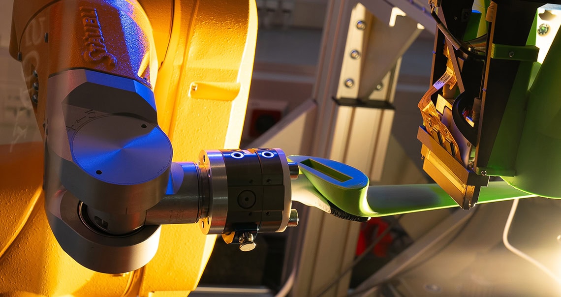 Roboterarm mit eingespanntem Leichtbauteil und Druckkopf