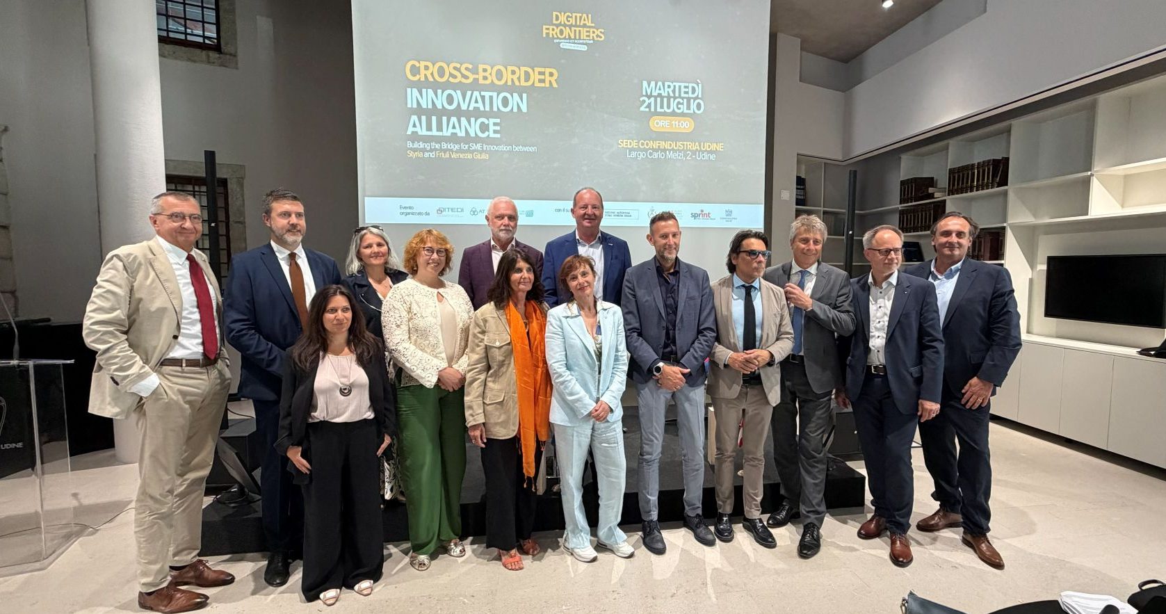 Cross-Border Innovation Alliance: Konferenzteilnehmer in Udine vor einer Leinwand mit dem Logo.