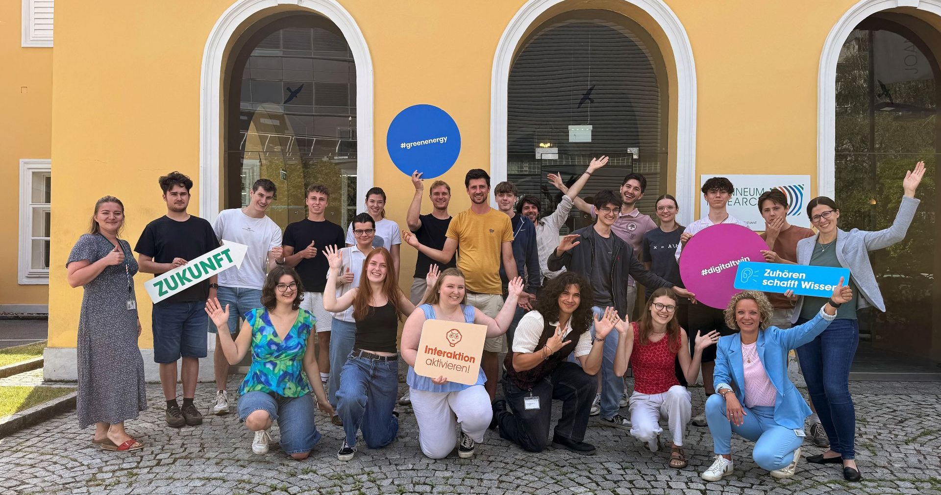 Jubelnde Praktikannten vor dem Eingang der Joanneum Research